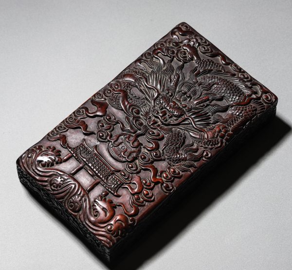 A CHINESE HUANGHUALI INKSTONE WITH DRAGON RELIEF.