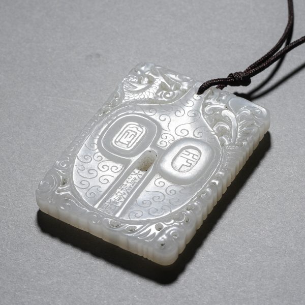 A CHINESE WHITE JADE PENDANT WITH DRAGON AND PHOENIX PATTERNS.