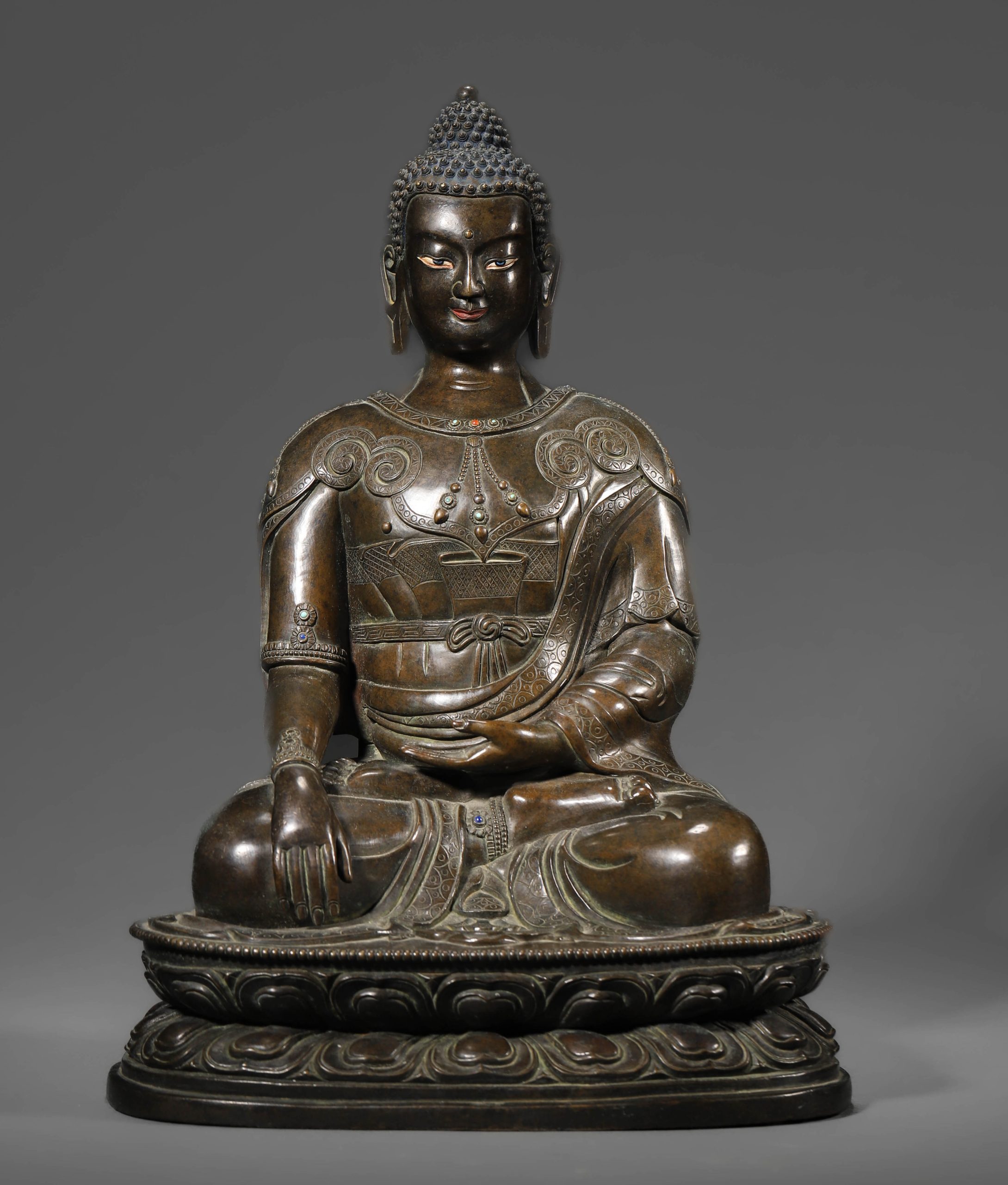 A CHINESE BRONZE SEATED SHAKYAMUNI FIGURE WITH INLAY, POSSIBLY QING DYNASTY, 18TH–19TH CENTURY.
